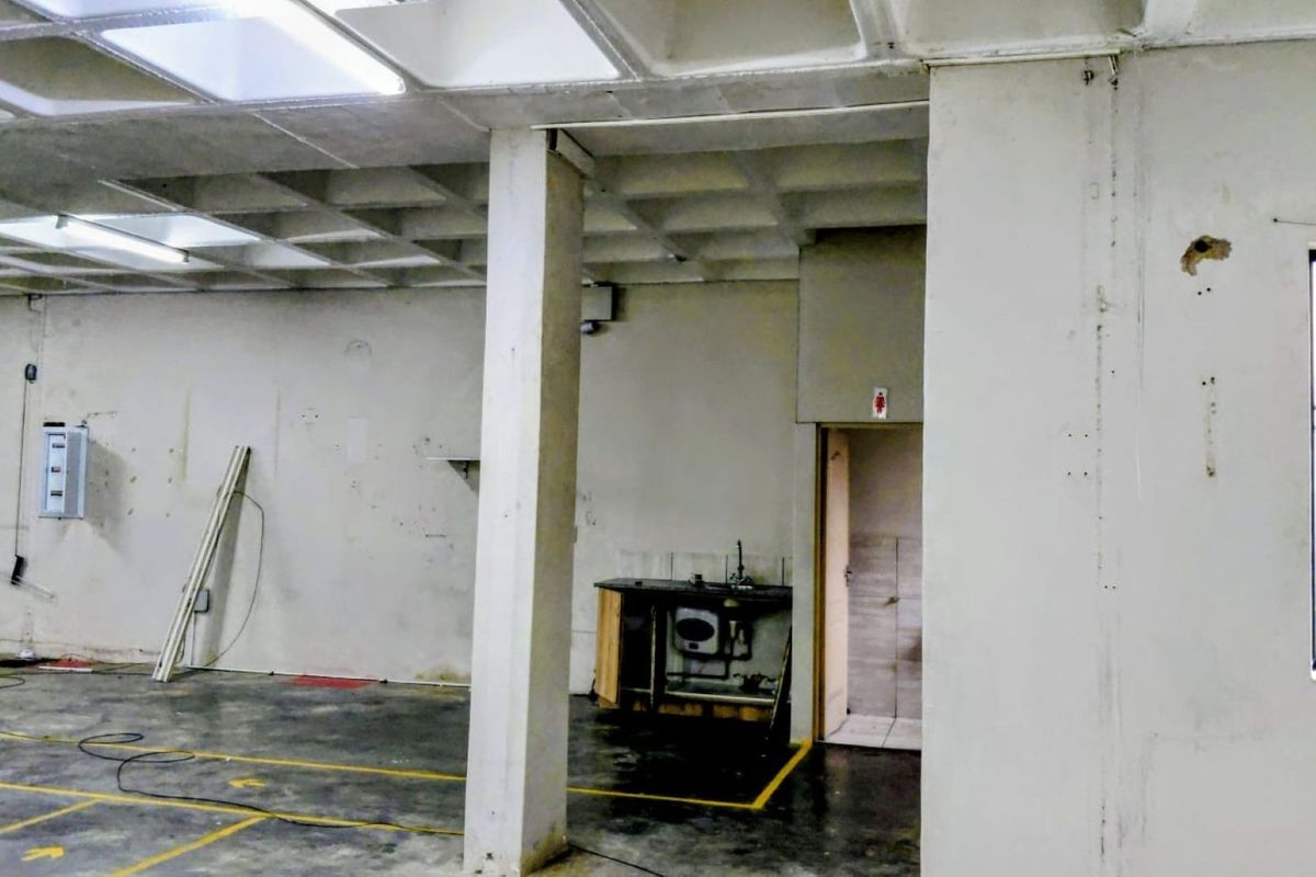 Open-plan industrial utility space featuring a waffle slab ceiling, concrete flooring, a small kitchenette area, and an integrated electrical distribution board.