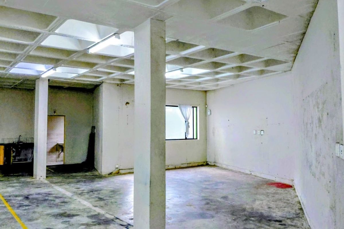 Spacious industrial open-plan area featuring a distinctive waffle slab ceiling, concrete flooring, and structural columns, suitable for versatile commercial or workshop use.