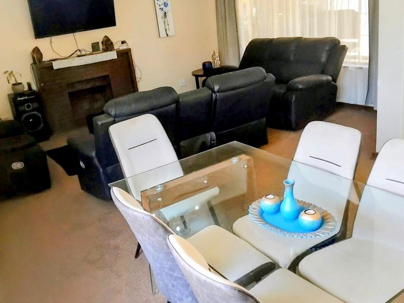 Open plan living and dining area featuring a fireplace and carpeted flooring.