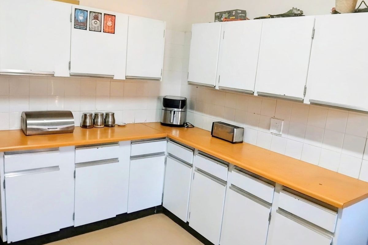 A functional kitchen featuring white cabinetry, laminate countertops, and a tiled backsplash, offering a clean and practical workspace.