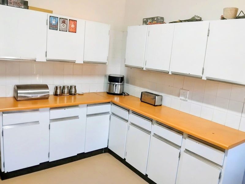 A functional kitchen featuring white cabinetry, laminate countertops, and a tiled backsplash, offering a clean and practical workspace.