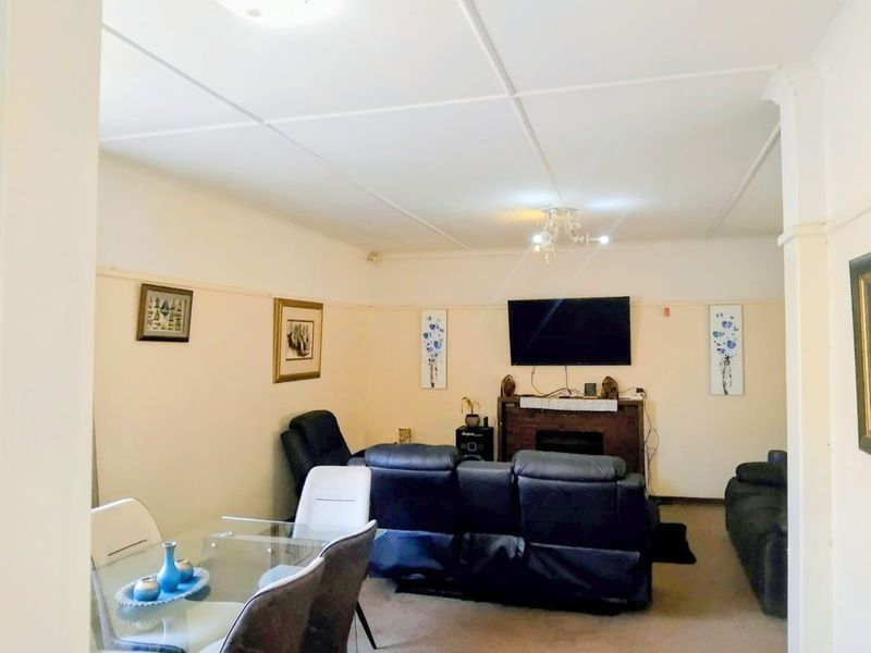 Open plan living and dining area featuring a fireplace and traditional ceiling tiles, offering a functional space for relaxation and meals.