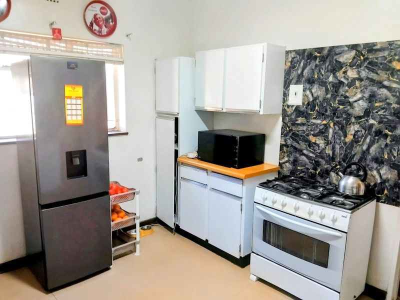 A functional kitchen featuring white cabinetry, a gas stove with oven, and a decorative stone-look splashback.