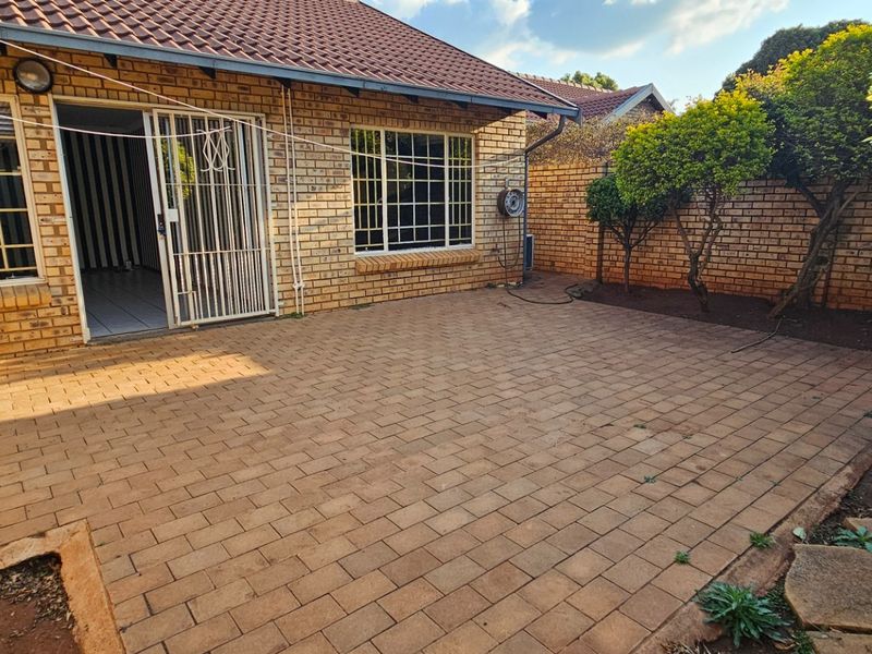 A private rear courtyard featuring brick paving, facebrick exterior walls, and a secure sliding door entrance to the home.