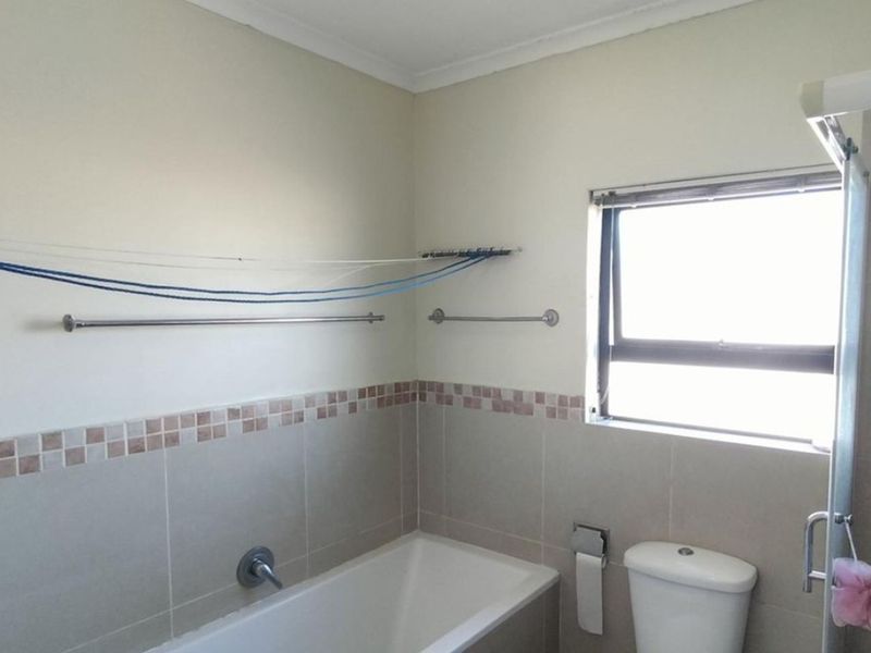 A functional bathroom featuring a bathtub, toilet, and tiled splashback, offering a clean and practical space for renovation or modernization.