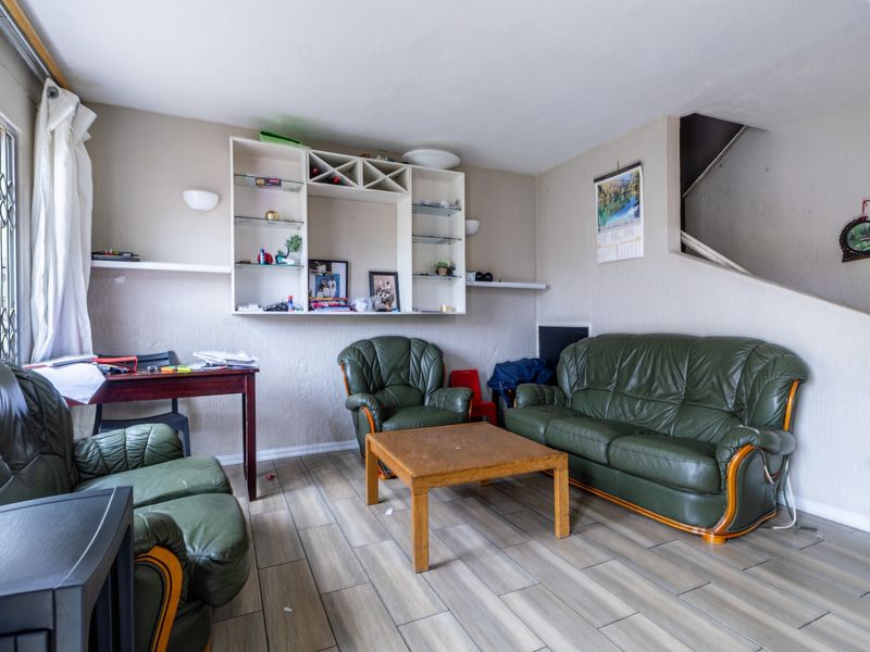 A living room featuring tiled flooring, a built-in shelving unit, and access to an internal staircase.