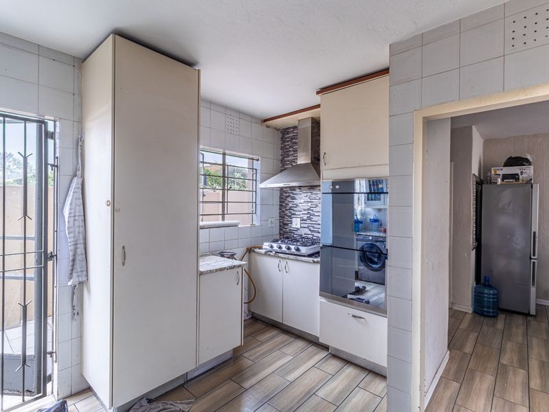 A compact kitchen featuring built-in cabinetry, a gas hob with extractor fan, and a built-in oven, with direct access to an outdoor area.