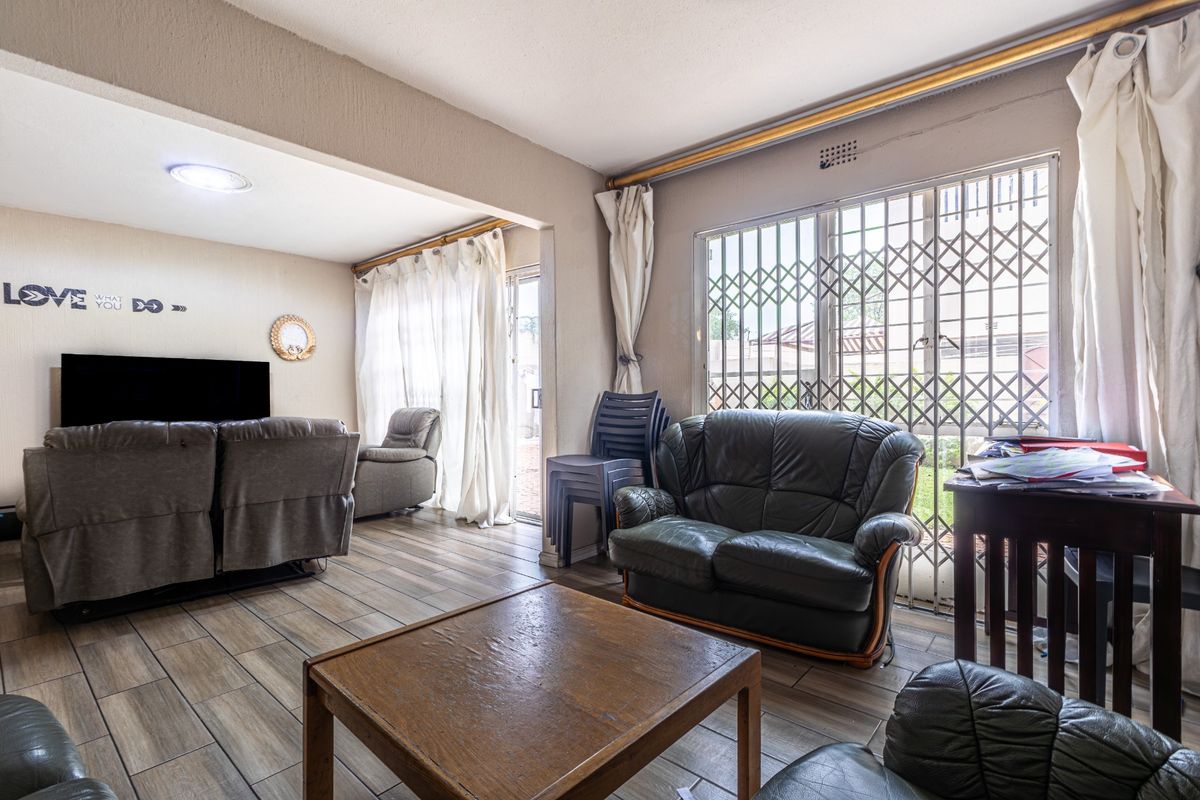 Spacious living area featuring tiled flooring, recessed lighting, and a sliding door with a security gate leading to the exterior.