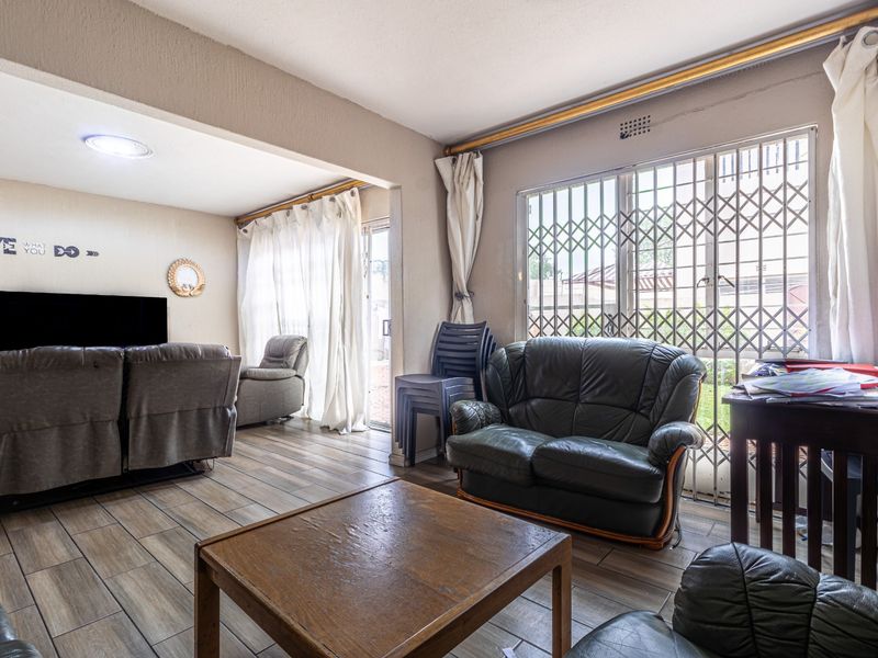 Spacious living area featuring tiled flooring, recessed lighting, and a sliding door with a security gate leading to the exterior.