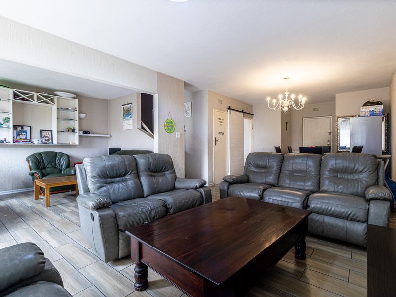 Spacious open-plan living area featuring tiled flooring, built-in shelving, and a sliding barn door, offering a versatile layout for comfortable family living.