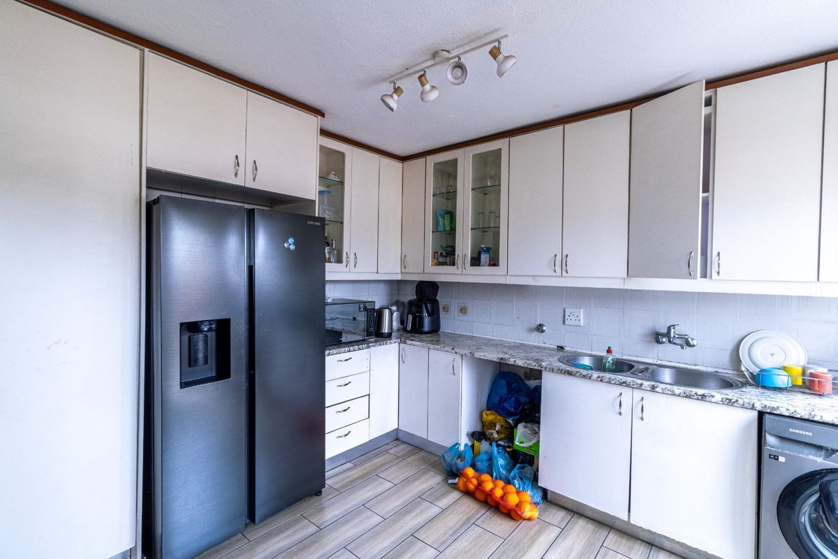 A functional kitchen featuring laminate cabinetry, granite countertops, a double bowl sink, and tiled flooring, offering a practical layout with ample storage space.