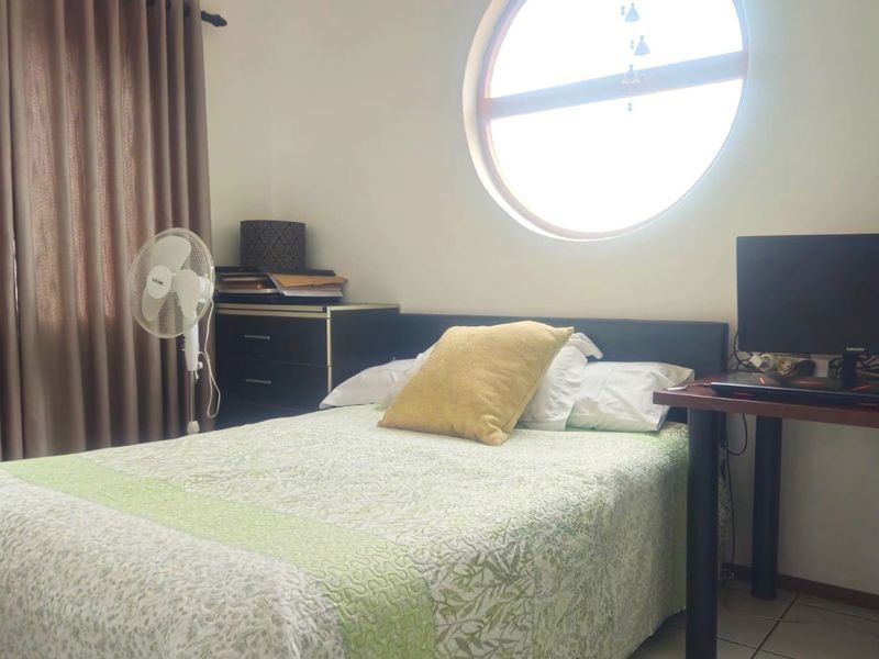 A bedroom featuring a distinctive circular window and tiled flooring, providing natural light and a unique architectural element to the space.