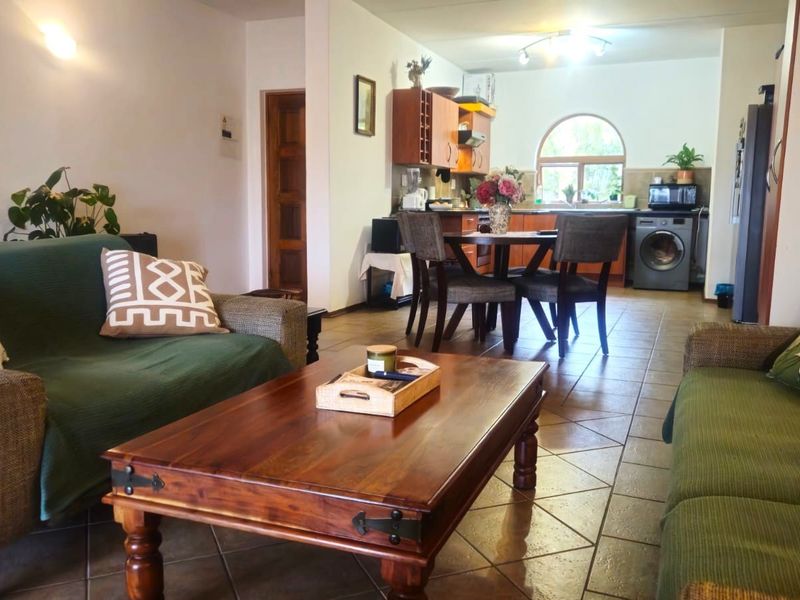Open-plan living and kitchen area featuring tiled flooring, built-in cabinetry, and an arched window, creating a functional and connected living space.