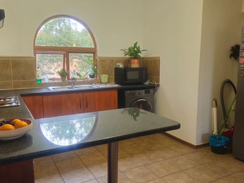 A functional kitchen featuring granite countertops, double basin sink, tiled backsplash, and an arched window providing natural light.