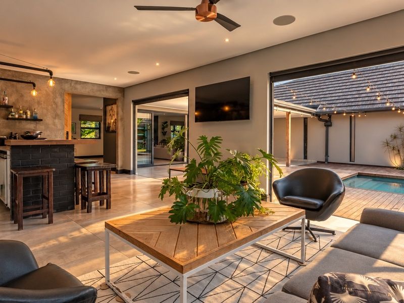 Spacious open-plan living area featuring a built-in bar, modern tiled flooring, and seamless indoor-outdoor flow to the pool deck through large sliding glass doors.