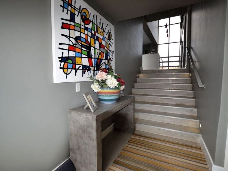 Modern entrance hall featuring a concrete staircase with integrated lighting and a large window, creating a bright and contemporary welcome area.