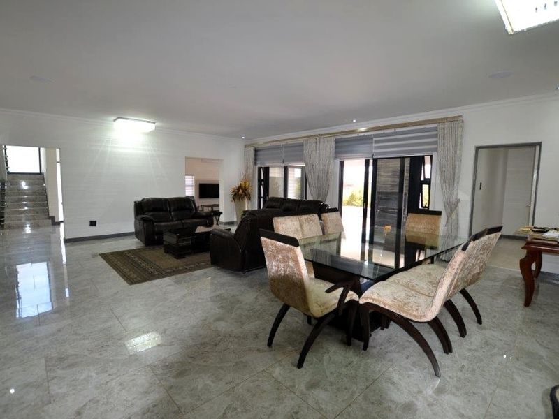 Spacious open-plan living and dining area featuring polished porcelain floor tiles, recessed lighting, and large sliding glass doors leading to the exterior.