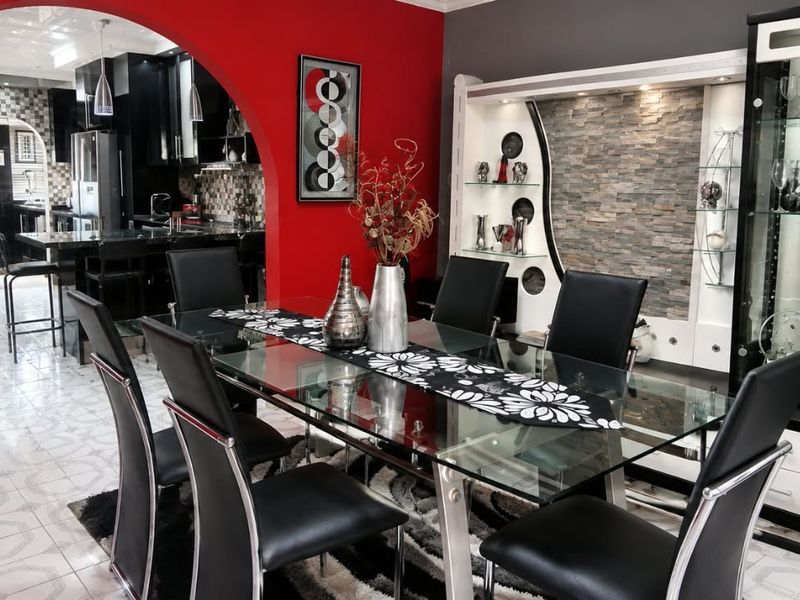 Open plan dining and kitchen area featuring a stone veneer feature wall, built-in display cabinetry, and a distinctive red arched entryway.