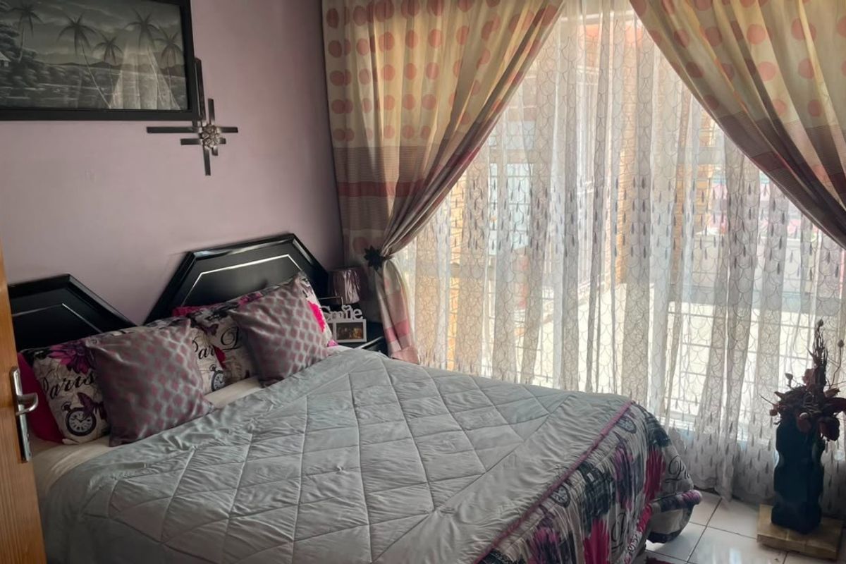 A bedroom featuring tiled flooring and a sliding glass door with an integrated security gate, providing access to the exterior.