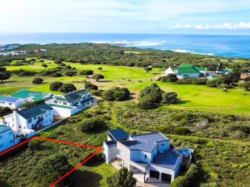 Aerial view of a vacant residential plot situated in a coastal estate, adjacent to a golf course with ocean views.