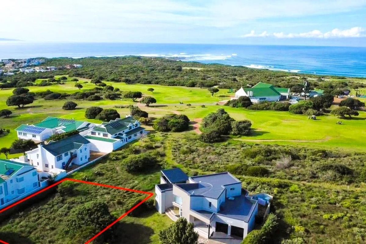 Aerial view of a vacant residential plot situated in a coastal estate, adjacent to a golf course with ocean views.