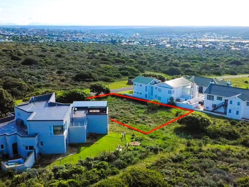 An aerial view of a vacant residential plot situated in a coastal neighborhood, highlighting the available land area and surrounding environment.