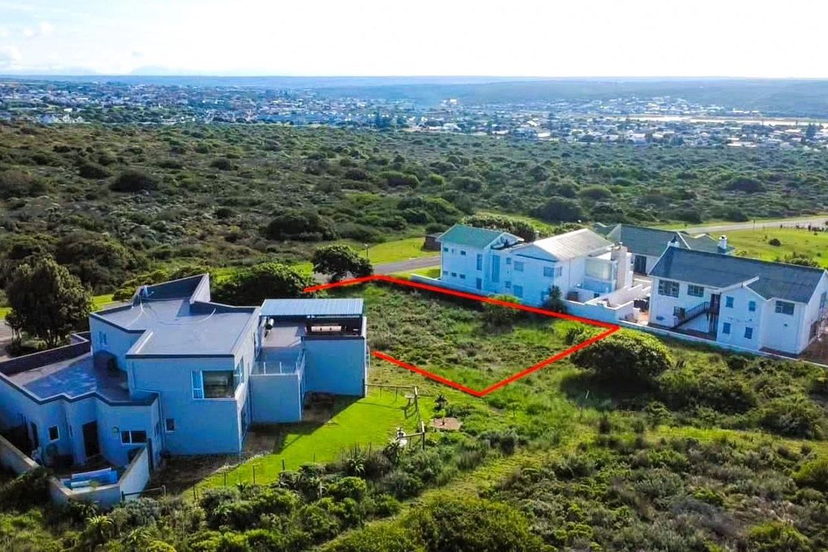 An aerial view of a vacant residential plot situated in a coastal neighborhood, highlighting the available land area and surrounding environment.