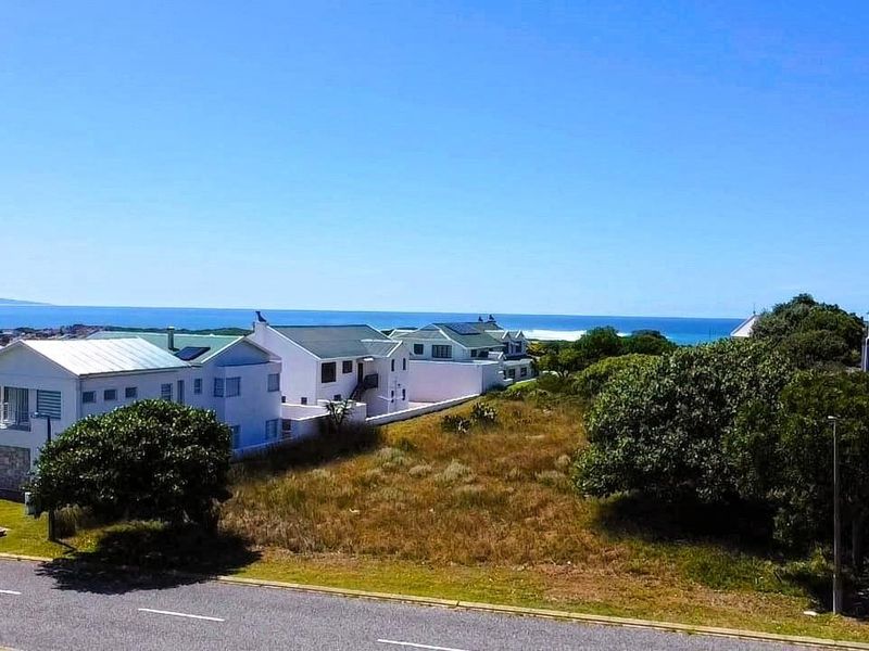 An aerial view of a vacant residential plot situated in a coastal neighborhood with ocean views.