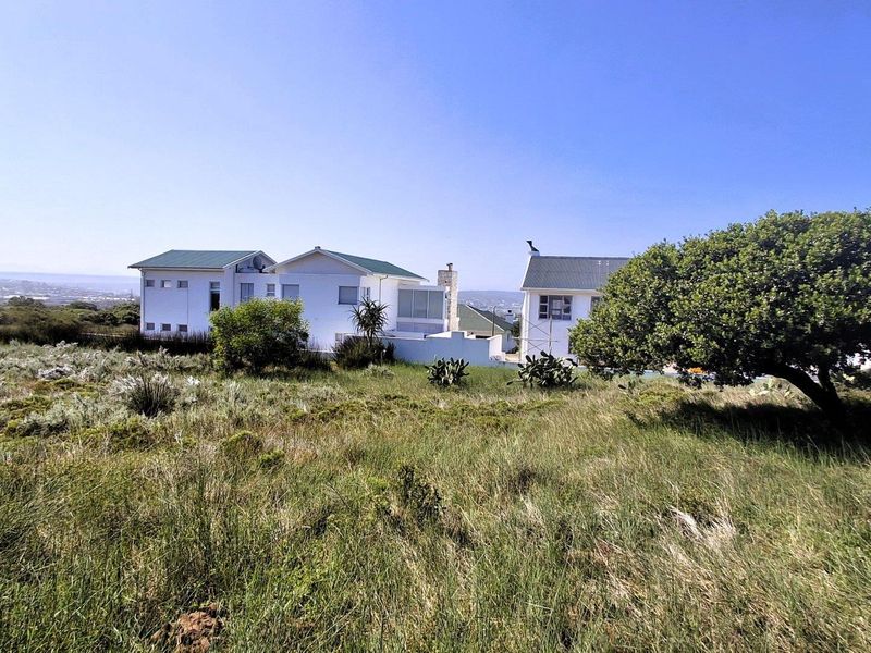 A view of the rear elevation of the residential property, featuring white facades, pitched roofs, and a surrounding natural landscape.