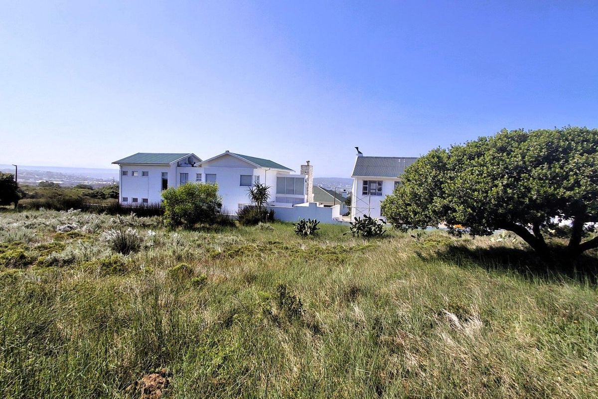 A view of the rear elevation of the residential property, featuring white facades, pitched roofs, and a surrounding natural landscape.