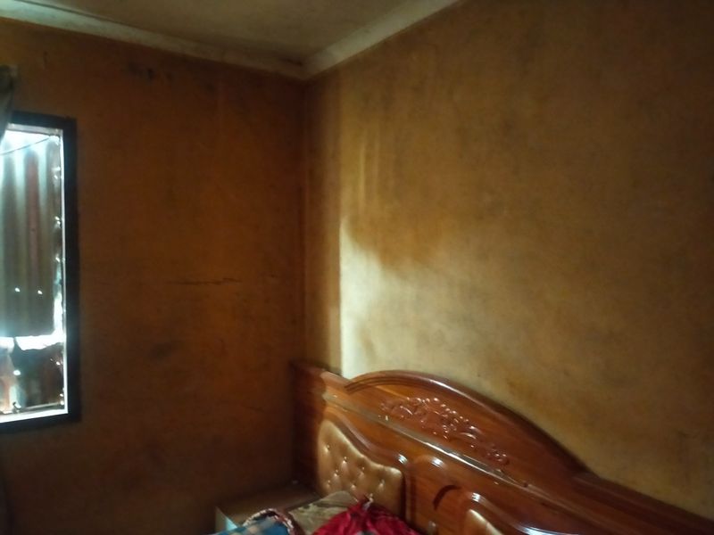A bedroom interior featuring dark, stained wall finishes requiring cosmetic attention and refurbishment.