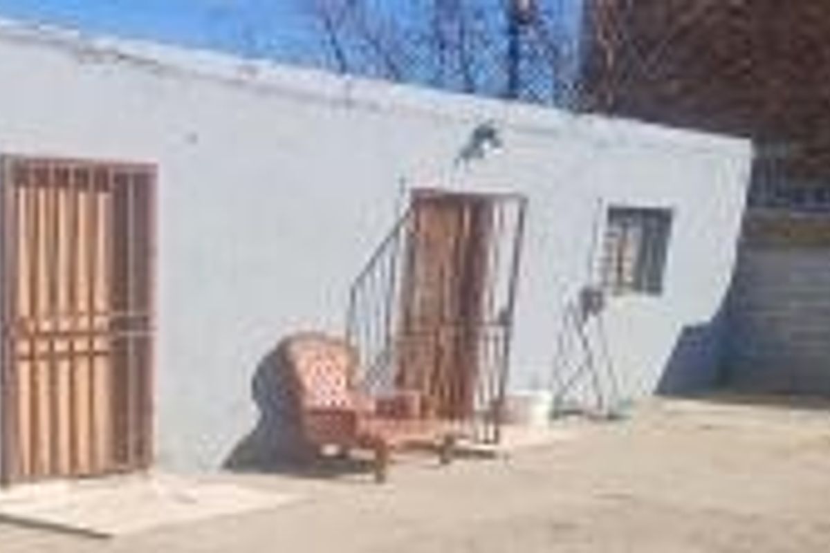 Rear exterior view of the property featuring a plain wall, security gates, and security bars on the windows.