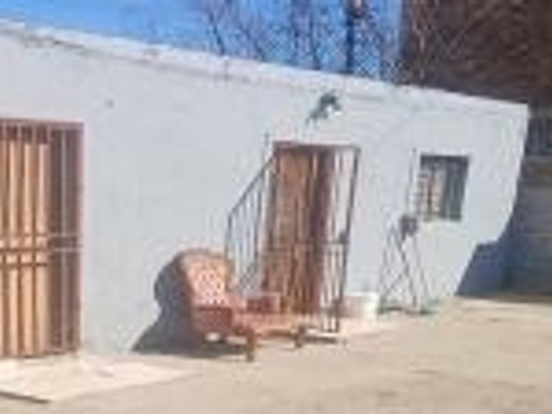 Rear exterior view of the property featuring a plain wall, security gates, and security bars on the windows.