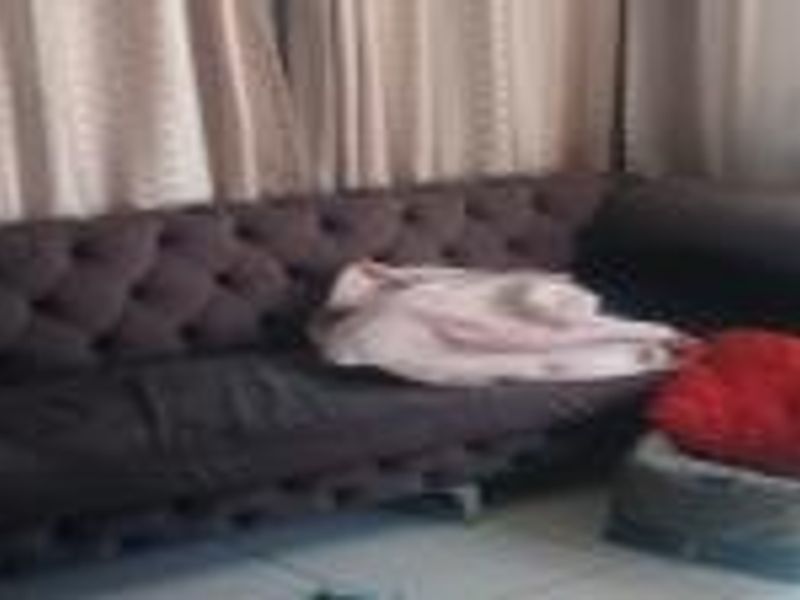 A living room area featuring tiled flooring and curtained windows.