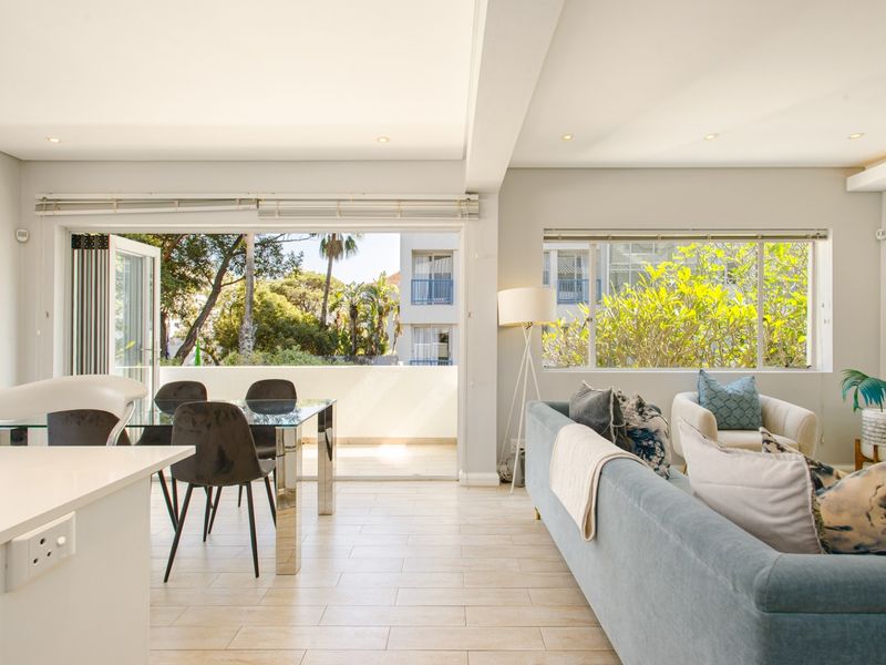 Bright open-plan living and dining area featuring tiled floors, recessed lighting, and large sliding doors opening onto a private balcony.
