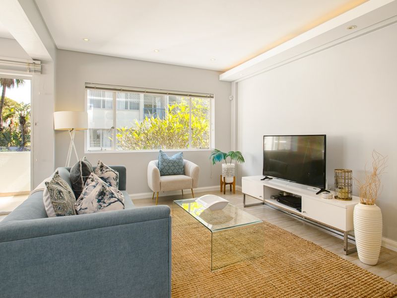 Bright and modern living room featuring recessed ceiling lighting, cove lighting, tiled floors, and direct access to an outdoor balcony area.