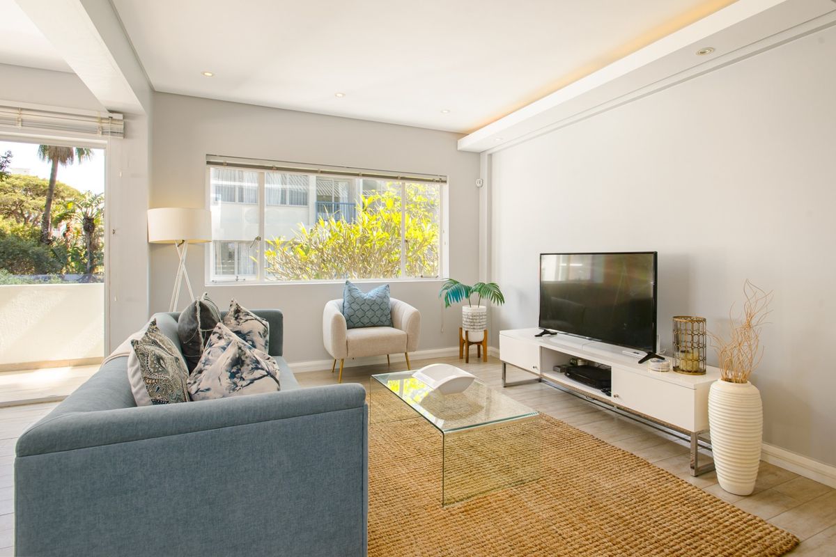 Bright and modern living room featuring recessed ceiling lighting, cove lighting, tiled floors, and direct access to an outdoor balcony area.