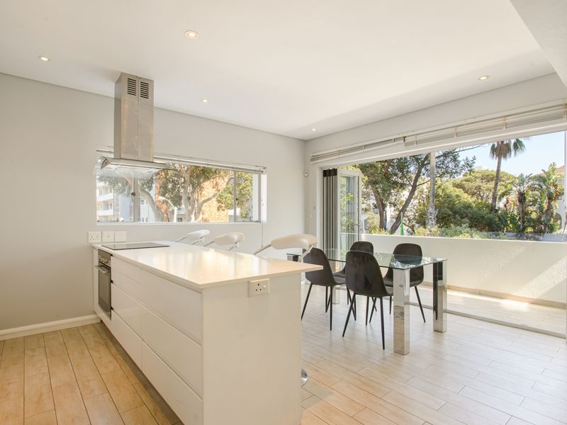 Modern open-plan kitchen and dining area featuring a sleek island, built-in appliances, and large sliding doors opening onto a private balcony.