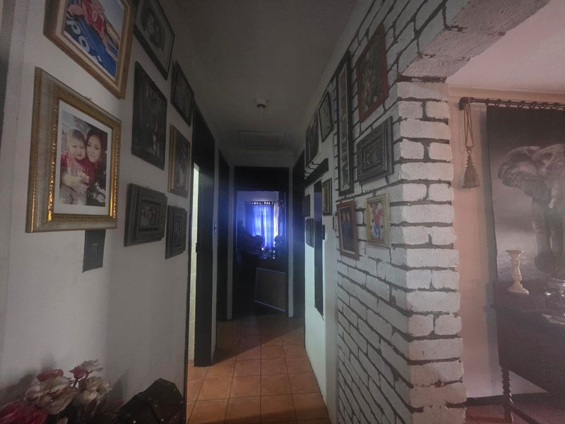 A hallway featuring an exposed brick wall, tiled flooring, and an arched entryway leading to other areas of the home.