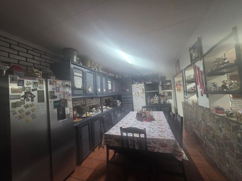 A kitchen and dining area featuring built-in cabinetry, exposed brickwork, and tiled flooring, offering a functional space with potential for modern updates.