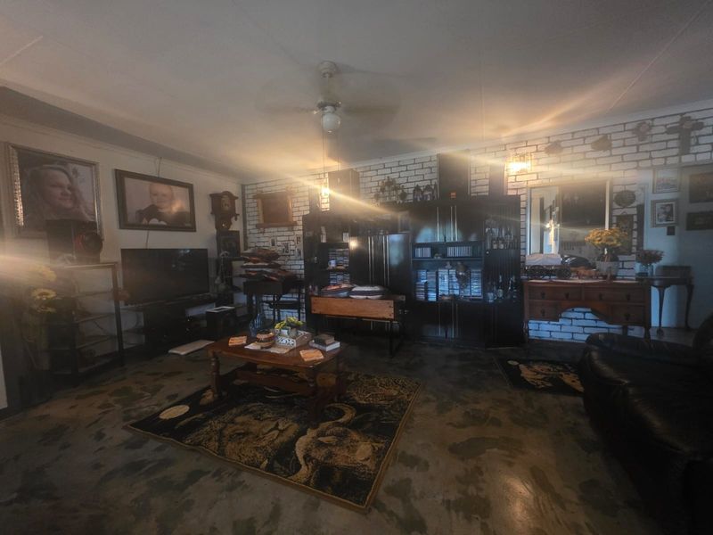 Living room featuring an exposed brick wall and ceiling fan, with a concrete floor finish.