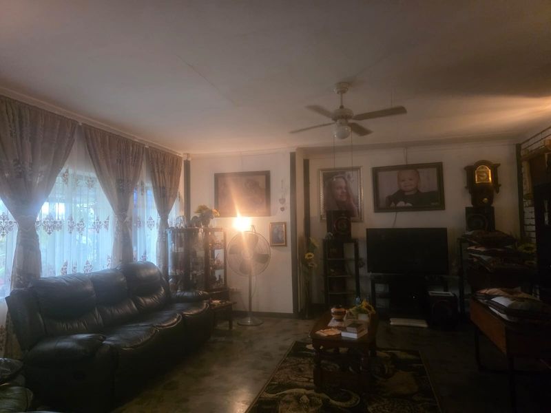 A living room area featuring a ceiling fan and large windows with curtain rails, providing a functional space for relaxation.