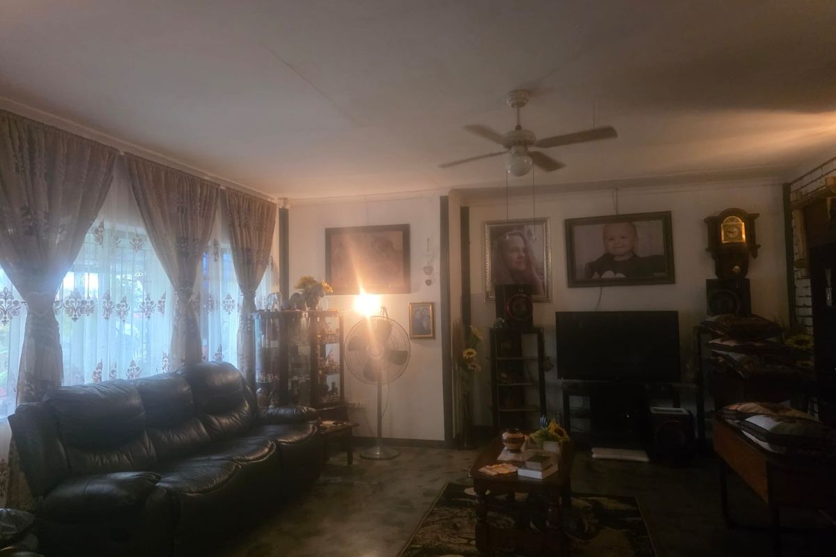 A living room area featuring a ceiling fan and large windows with curtain rails, providing a functional space for relaxation.