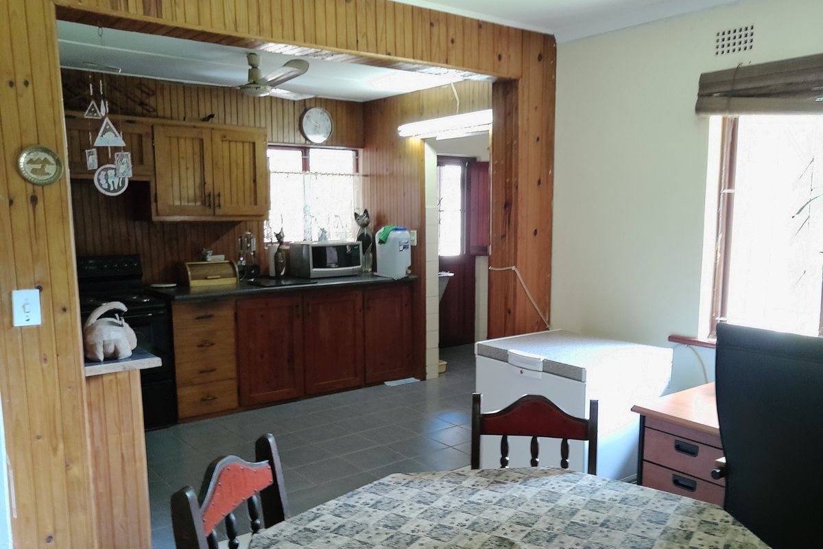 A dated kitchen featuring extensive wood paneling, tiled flooring, and built-in cabinetry, offering significant potential for a modern renovation.
