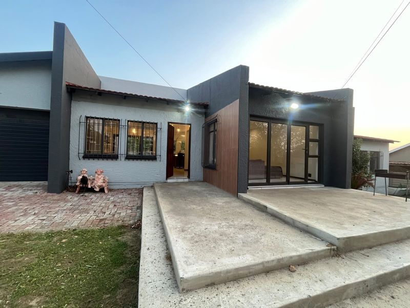 Front elevation of the house featuring a concrete patio, sliding glass doors, and modern timber cladding accents.