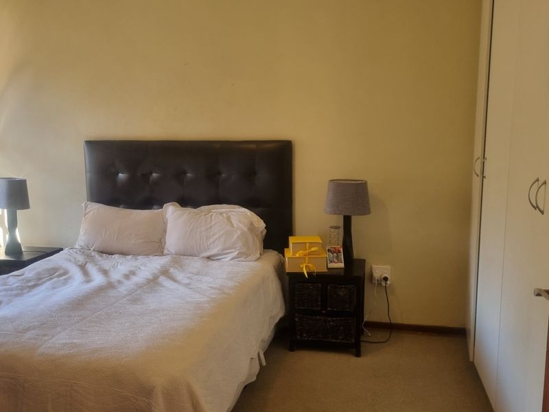 A standard bedroom featuring neutral wall tones, carpeted flooring, and a built-in wardrobe for storage.