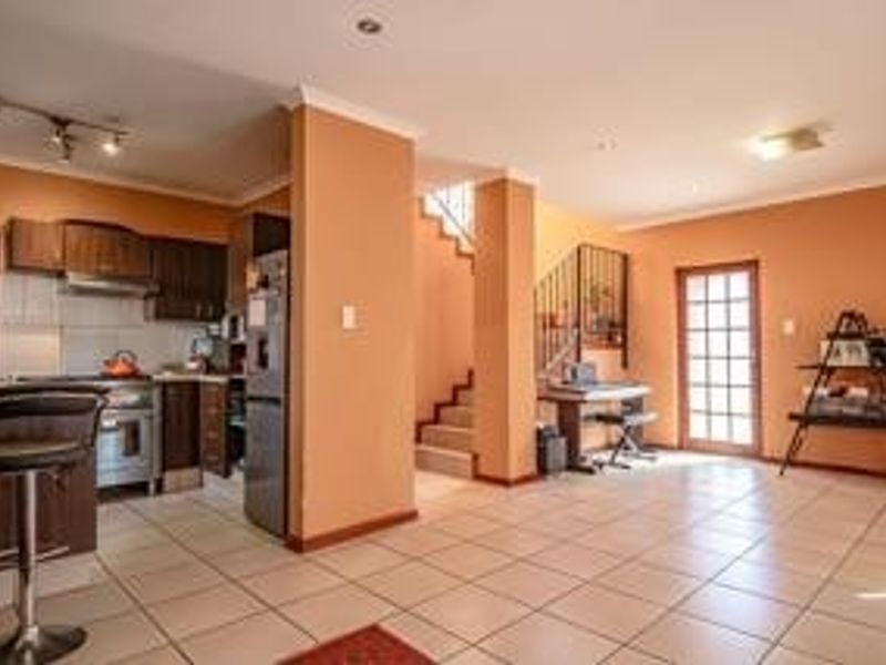 Open plan kitchen and living area featuring tiled floors, built-in cabinetry, and a staircase leading to the upper level.