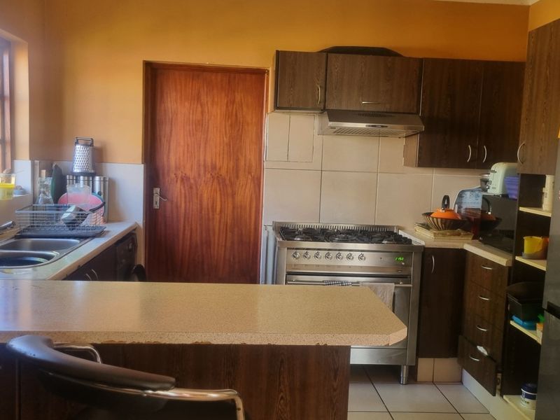 A functional kitchen featuring dark wood cabinetry, a stainless steel gas stove with extractor fan, tiled backsplash, and a convenient breakfast counter.