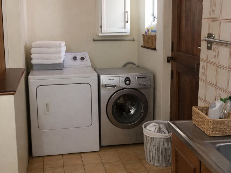 Functional laundry room featuring tiled flooring, built-in cabinetry with a stainless steel sink, and wall-mounted storage, providing a practical utility space.