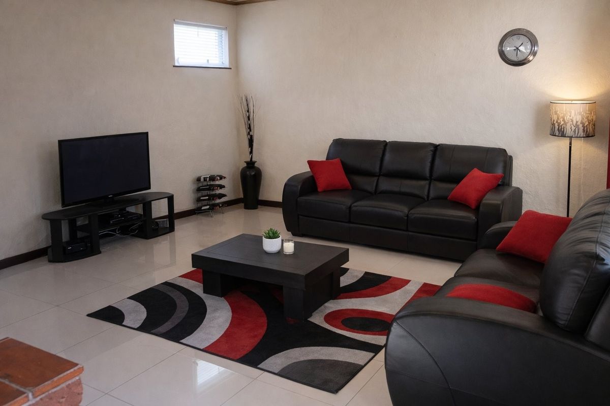 A living room featuring neutral walls, polished tiled flooring, and a small high-level window, providing a functional and well-lit space.
